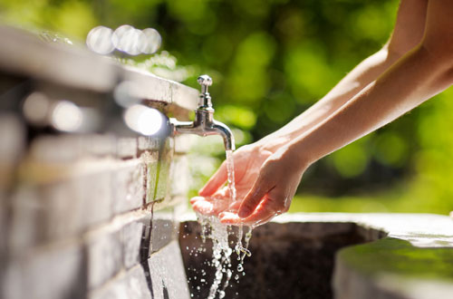 person washing hands in faucet
